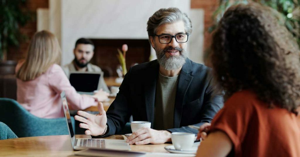 Man and woman sat with coffee discussing business coaching