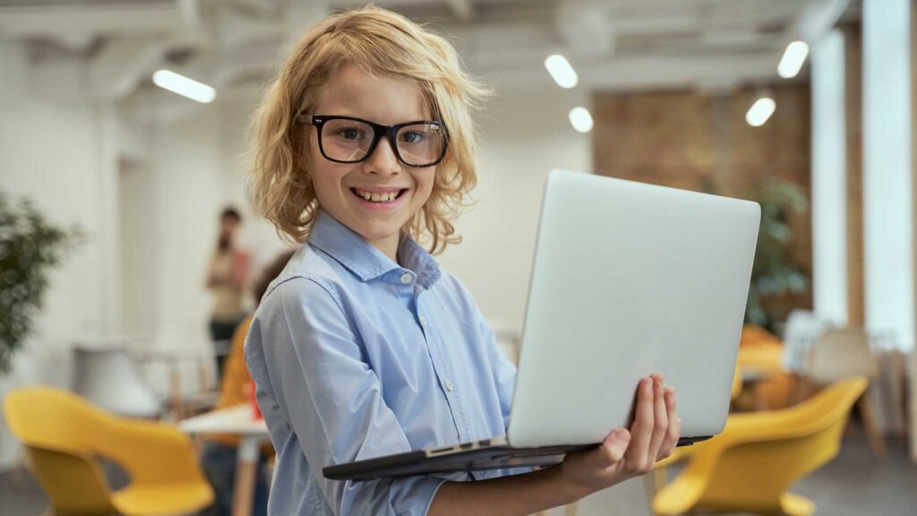 Picture of a boy holding a laptop - 20 jobs that never existed in 2000.